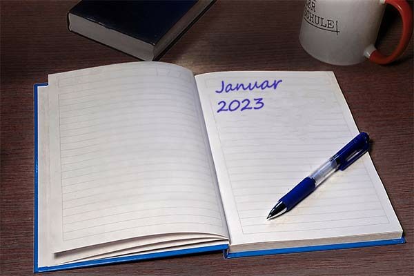 Aufgeschlagenes Notizbuch auf einem Schreibtisch. Oben rechts steht "Januar 2023", darunter liegt ein Stift.