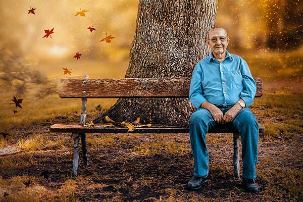 Alter Mann auf einer Bank in einer Herbstlandschaft