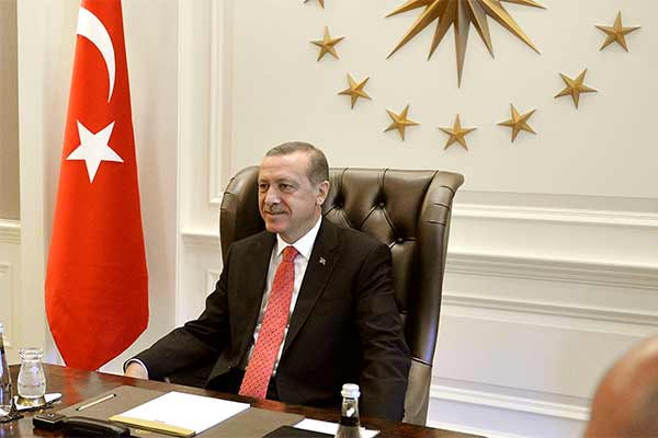 Erdogan im Präsidentenpalast, sitzt am Schreibtisch, neben ihm die türkische Flagge