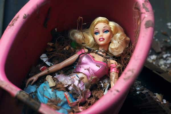 Abgenutzte, schmutzige Barbie liegt in einem Mülleimer